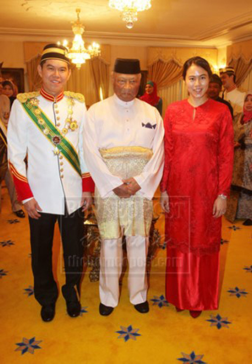 夏忠招（左）和妻子林芫（右）与已故彭亨州苏丹阿末沙陛下（中）的合影。（取自《The Borneo Post》）