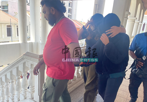 女被告（右）在亲友陪同下步离法庭，她用外套连身头套遮脸，避免真面目曝光。

