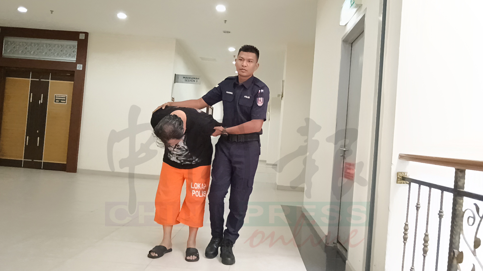 被告一度弯身，低下头避开记者的摄影镜头，不肯前行。