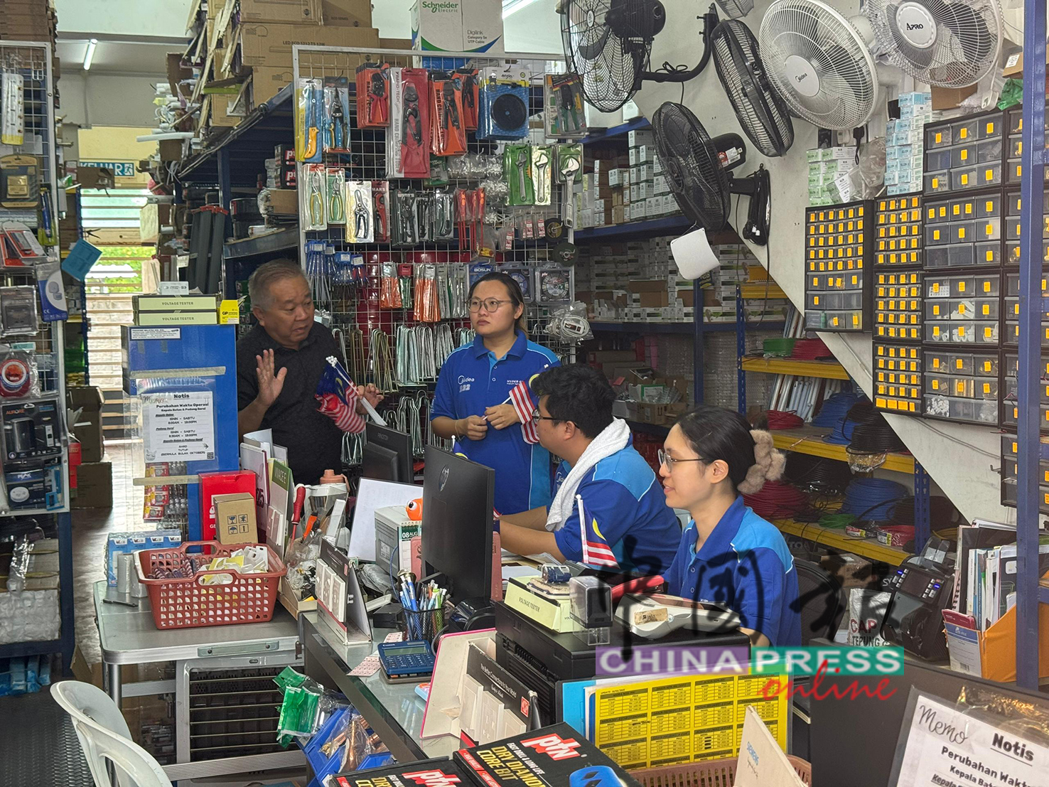 赖国平（左）向附近商家问好。