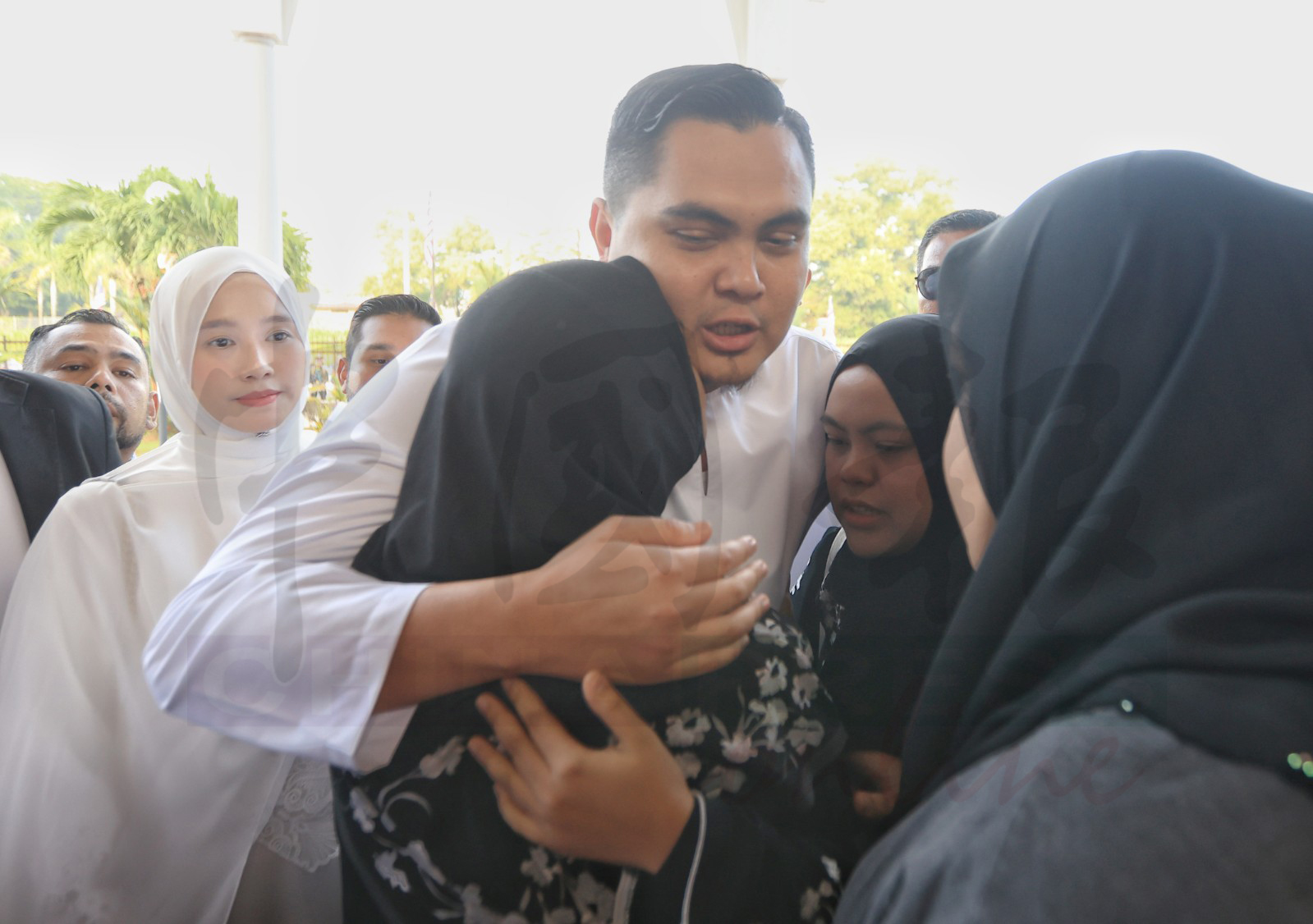 阿克马母亲(背对镜头者)陪他出庭,拥抱他为他打气。