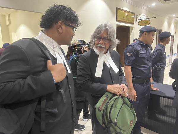 其中一名被告的代表律师拿督兰星(左2)准备进入地庭。