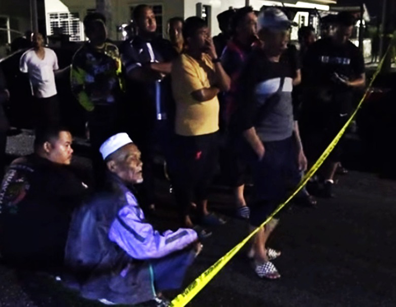 男死者的父亲，坐在警戒线外，看着警方展开调查工作。