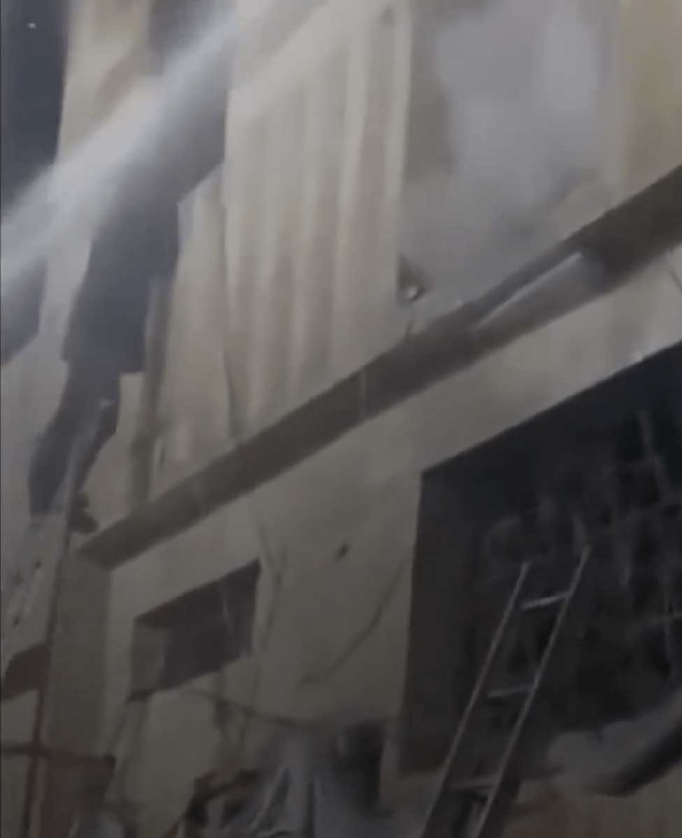 火场有浓烟冒出，消防员射水扑救。