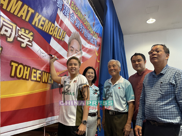 杜依蔚（左）肩负世界冠军的荣耀回到文化学校，并在海报上签名留念。右起为王天财、郭子毅、佘贵忠及王姝郿。

