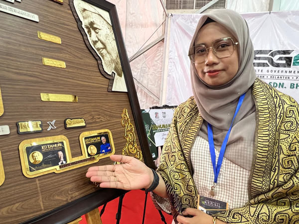 努鲁展示印有马哈迪肖像的2枚特别版纯金纪念币。