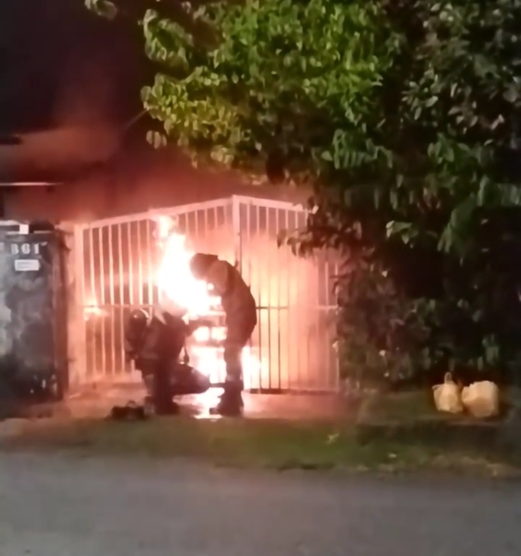 消拯员电锯锯开篱笆门的铁条后，冲入屋内灭火。