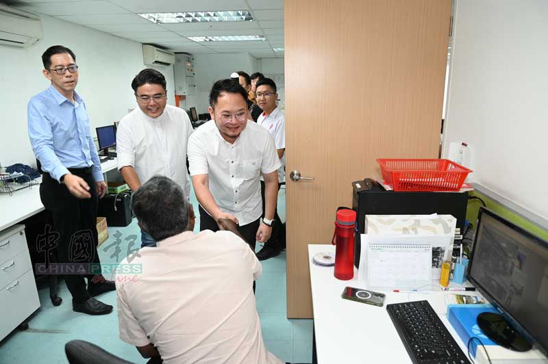 林明标（左）带领吴家良和林骏荣等人参观编采部。
