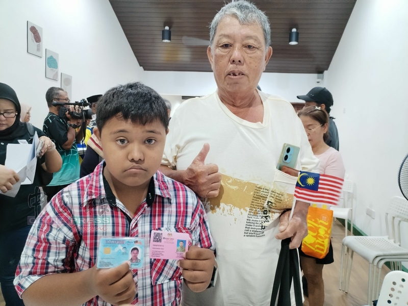 张正阳（左起）在父亲张月庆陪同下，出示其大马卡及残疾人士卡。