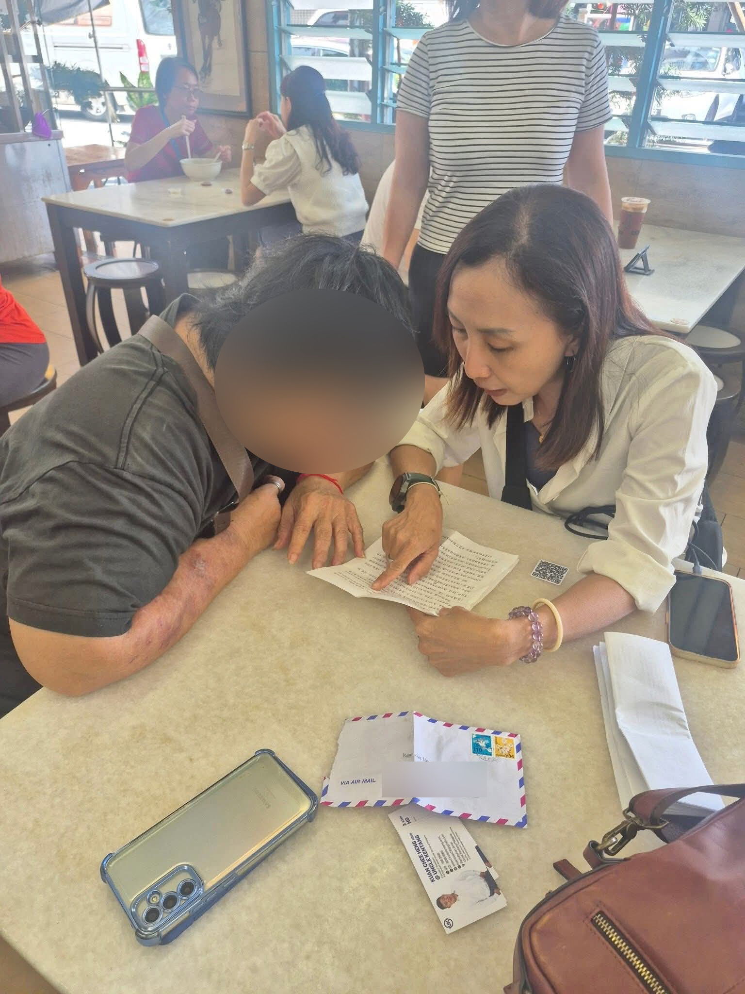 妇女(左)聆听关志庭的团队读出女儿所书写的信函内容。