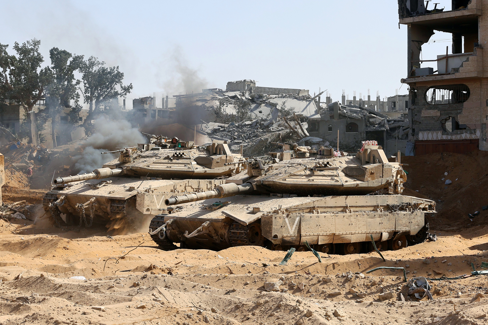 以色列军队坦克和装甲运兵车周五驻扎在加萨城约旦野战医院附近的建筑废墟中。（美联社）