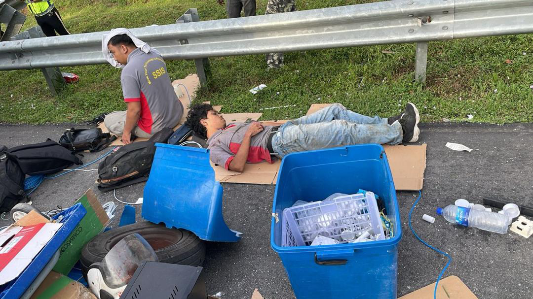 客货车南北大道发生意外后，其中2名受伤乘员被救出后在路旁休息及接受治疗。