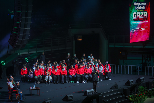 安华（中）在大会上发表演讲；身后则上出席集会的23名早前遭以色列扣留的大马志工。（马新社）