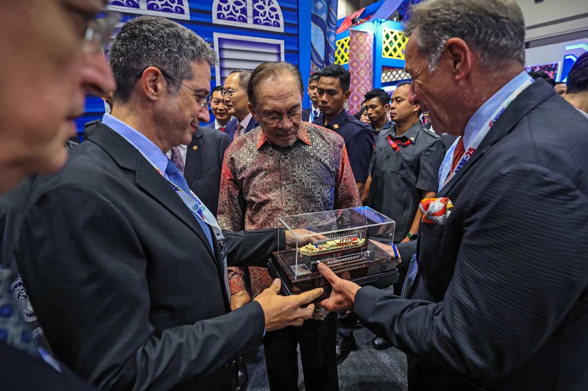 参展商向安华（中）展示邮轮模型，讲解邮轮构造。