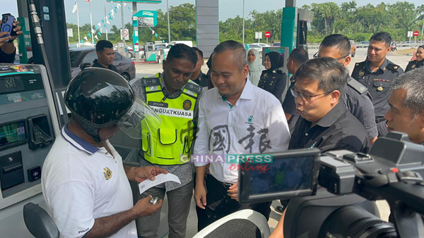 杰根（左2）与油站业者，协助民众如何使用BUDI 95机制。