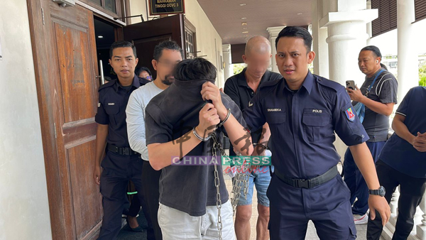 25岁被告面控后，被庭警带离法庭时，用衣服遮挡脸部。