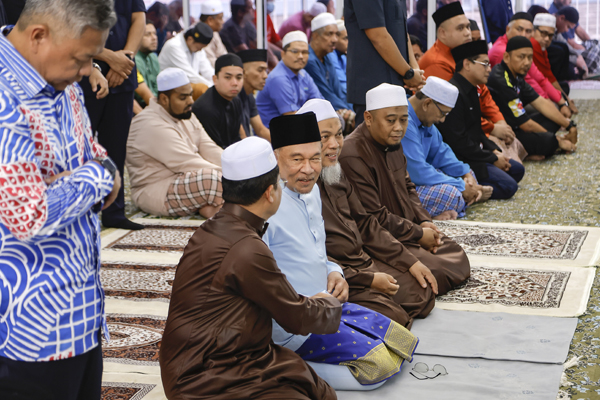 安华(第一排左2)在祈祷时与民众友好交流。