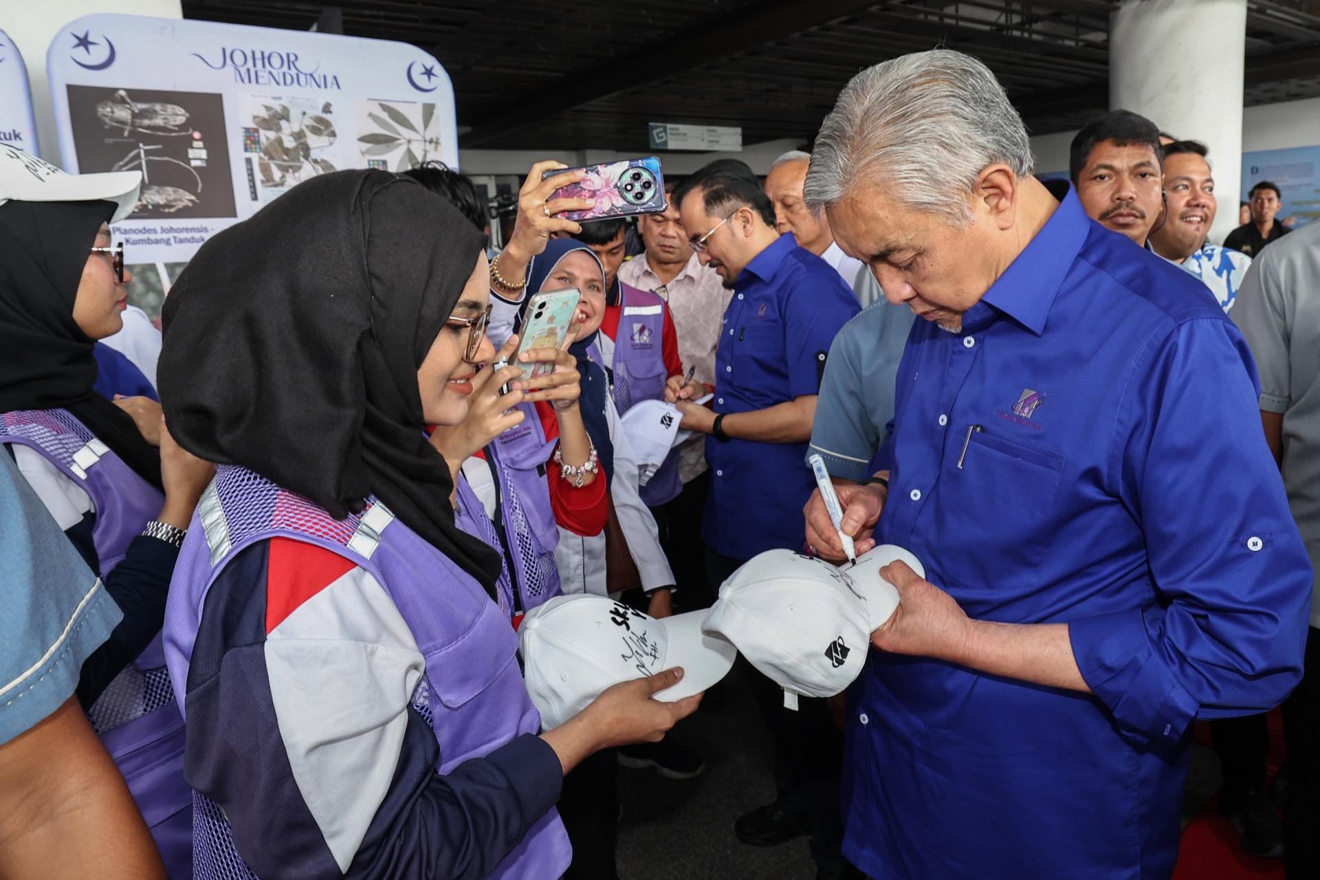 阿末扎希（右）在活动上，为支持者签名。