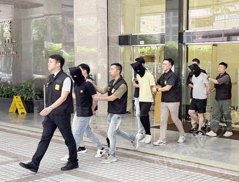 澳门警方将3名来自马来西亚和香港的蒙面嫌犯押出警局。