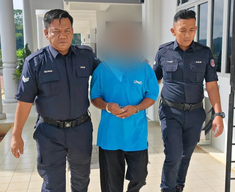 被告(中)被两位庭警押离劳勿地庭。(图:KOSMOS)