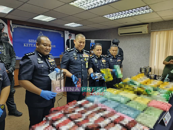 拉哈曼(左2)和肃毒组警员一起展示所起获的各类毒品。