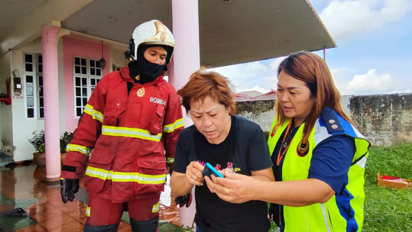 消拯人员将吴丽芳（左2）在逃生时来不及取走的手机，交还给后者。