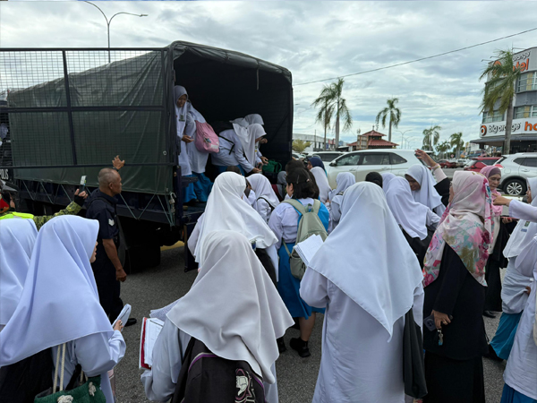 日得拉国中的女考生，排队上警方卡车准备到另一个考场。