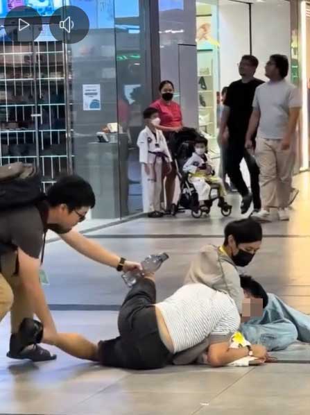 另一名男子了解来龙去脉后，便移动白衣男的双腿，使其呈趴在地上的状态。